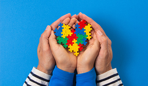 two hands holding a heart made of colorful puzzle pieces on a blue background celebrating 17 years of teamwork and love