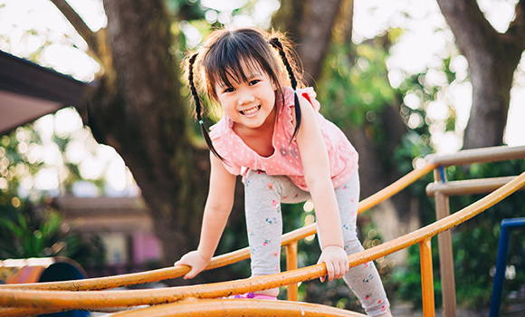 smiling girl playing on playground equipment during daytime engaging in outdoor activity and exploring her surroundings with joy 12 fun moments 12 adventures 12 skills 12 playtime