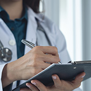 female doctor holding clipboard and pen with two medical tools in background