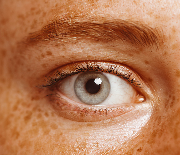 close up of a human eye featuring grey iris and freckles on skin with natural beauty emphasizing the number 9 in aesthetics and clarity