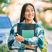 smiling student holding notebooks outdoors with greenery and soft sunlight reflecting in the background 9 important skills for students