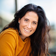 smiling woman in a yellow sweater with long dark hair showcasing confidence and joy in a sunny outdoor setting with a modern background related to personal growth and inspiration 2 tips for success