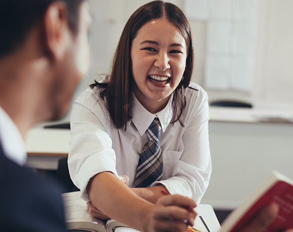 smiling student engaging in discussion with classmate in classroom setting highlighting friendship learning and joy of education ten moments of laughter